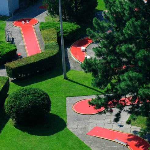 Picture of miniature golf course with landscaped trees, bushes and artificial turf